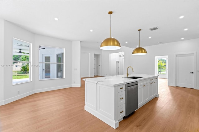 kitchen with pendant lighting, stainless steel dishwasher, sink, an island with sink, and white cabinets