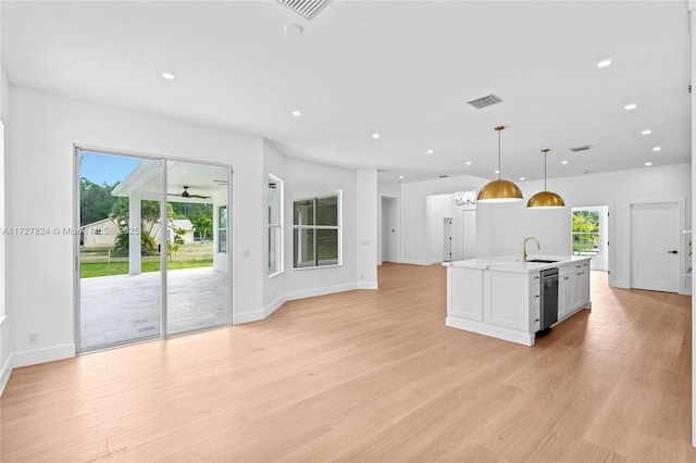 kitchen with light hardwood / wood-style floors, an island with sink, hanging light fixtures, white cabinets, and sink