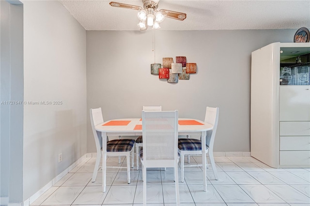 dining space with ceiling fan, light tile patterned floors, and a textured ceiling