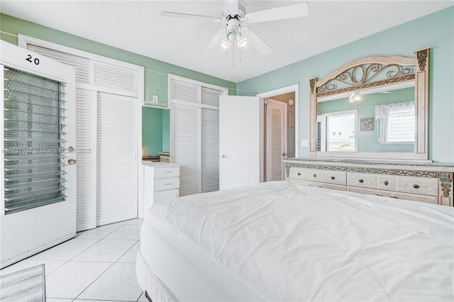 bedroom with ceiling fan, light tile patterned floors, and a textured ceiling