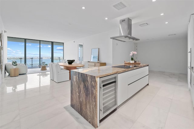 kitchen featuring wine cooler, a wall of windows, island exhaust hood, a water view, and white cabinets