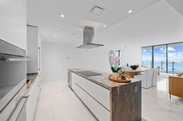 kitchen featuring white cabinetry, island range hood, stainless steel oven, a water view, and black electric cooktop