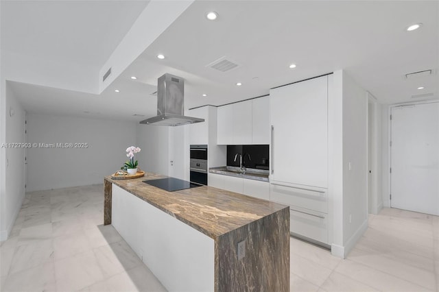 kitchen featuring white cabinetry, black electric stovetop, double oven, sink, and island range hood