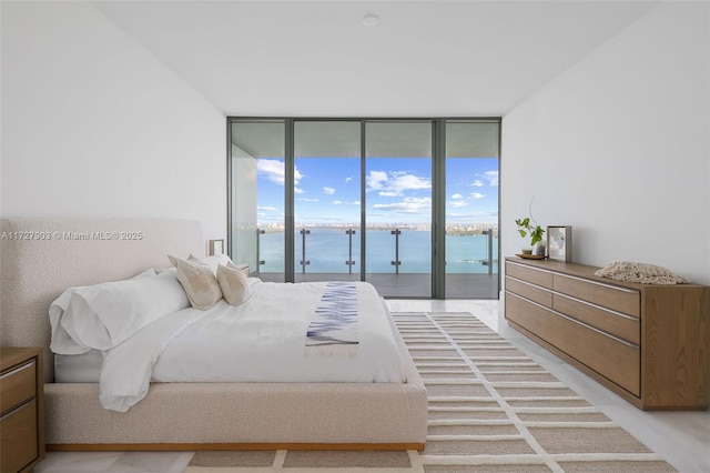 bedroom with floor to ceiling windows, access to outside, a water view, and light wood-type flooring