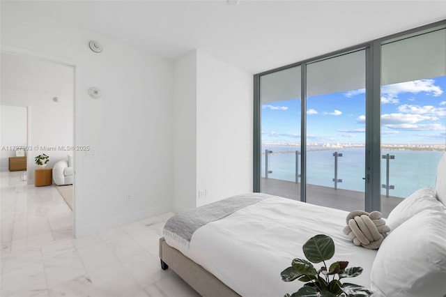 bedroom with a wall of windows, access to outside, and a water view