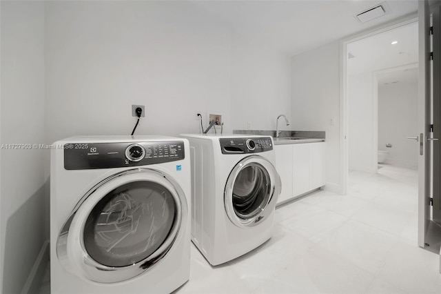 laundry area with sink, separate washer and dryer, and cabinets