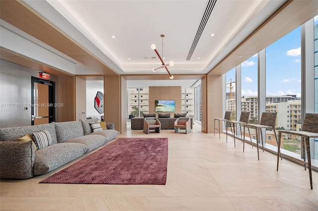 living room with floor to ceiling windows, a tray ceiling, and an inviting chandelier