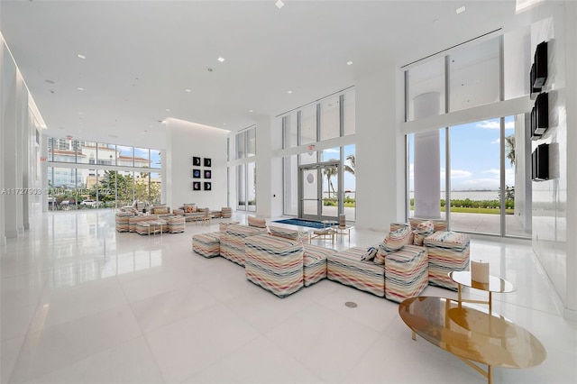 tiled living room featuring a wall of windows and a high ceiling