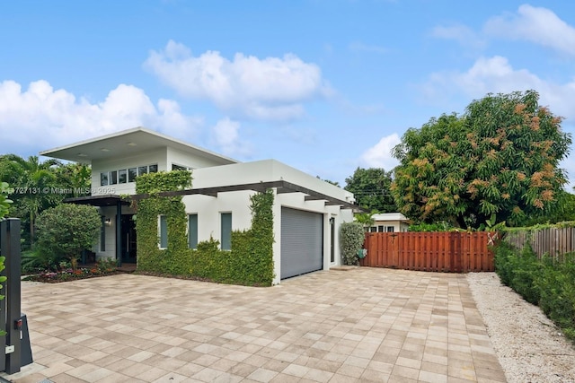 exterior space with decorative driveway, stucco siding, an attached garage, and fence