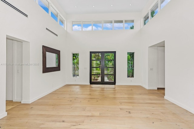 empty room featuring plenty of natural light, baseboards, visible vents, and light wood finished floors