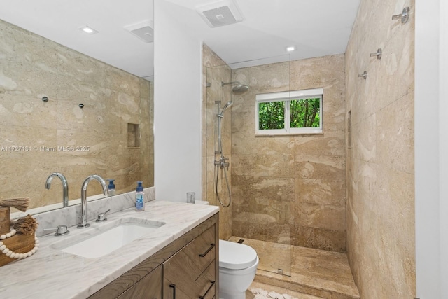bathroom featuring visible vents, toilet, vanity, and a walk in shower