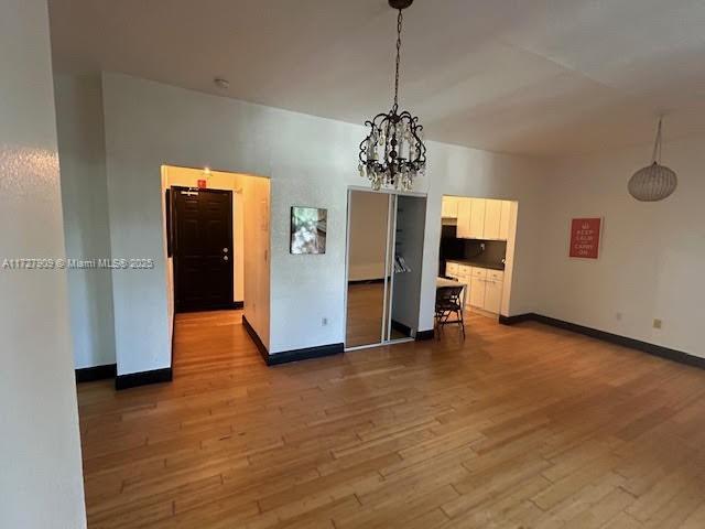 empty room with a chandelier and hardwood / wood-style floors