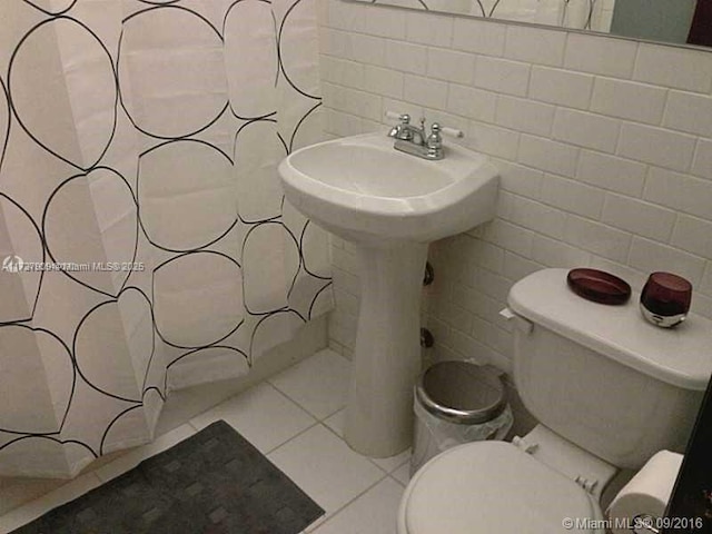 bathroom featuring decorative backsplash, tile walls, toilet, and tile patterned flooring