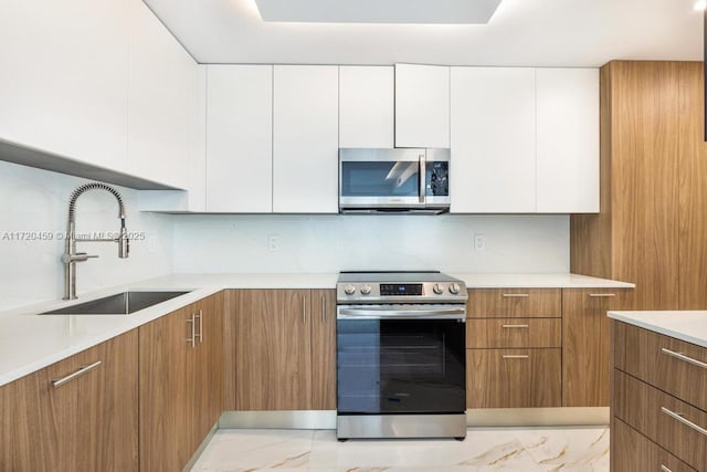 kitchen with white cabinetry, stainless steel appliances, backsplash, and sink