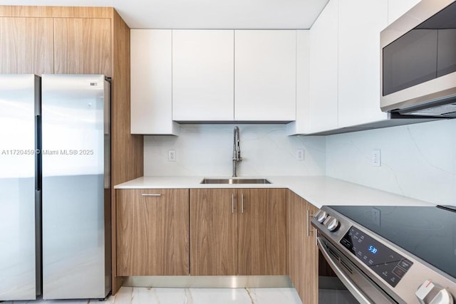 kitchen with tasteful backsplash, white cabinets, sink, and stainless steel appliances