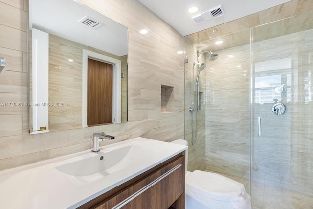 bathroom featuring toilet, tile walls, walk in shower, and vanity