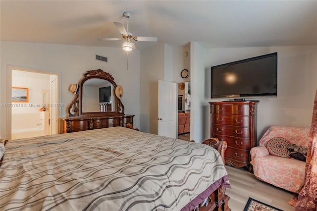 bedroom with ceiling fan, vaulted ceiling, connected bathroom, and light hardwood / wood-style flooring