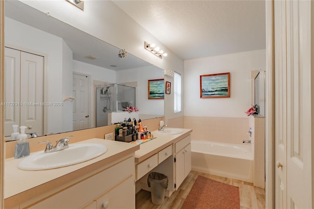 bathroom featuring a textured ceiling, separate shower and tub, and vanity