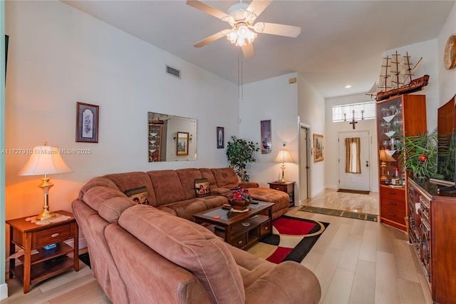 living room featuring light hardwood / wood-style floors, a high ceiling, and ceiling fan