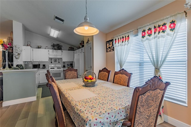 dining area with vaulted ceiling and dark wood-type flooring