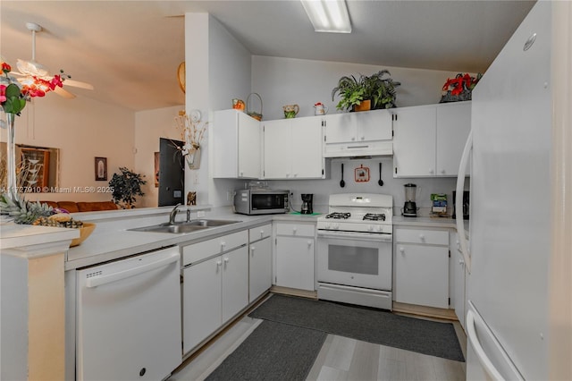 kitchen with kitchen peninsula, sink, white cabinets, and white appliances