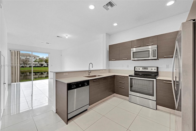 kitchen with light tile patterned floors, stainless steel appliances, dark brown cabinets, and sink