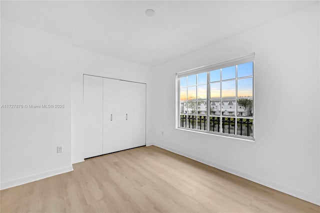 unfurnished bedroom with a closet and light hardwood / wood-style floors