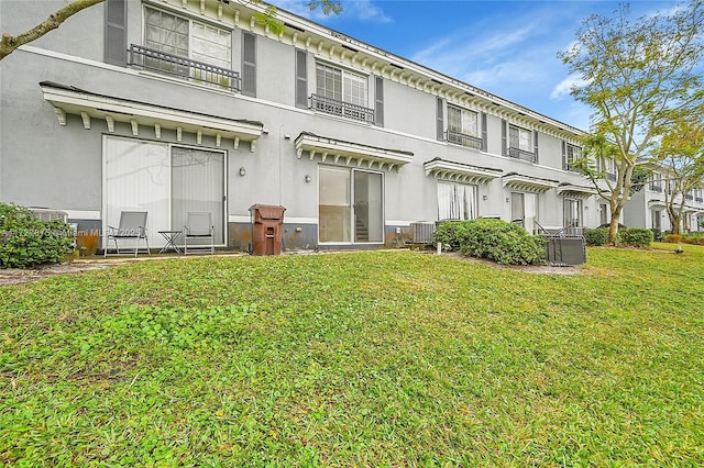 back of property featuring central AC unit and a lawn