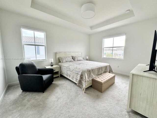 carpeted bedroom featuring multiple windows and a tray ceiling