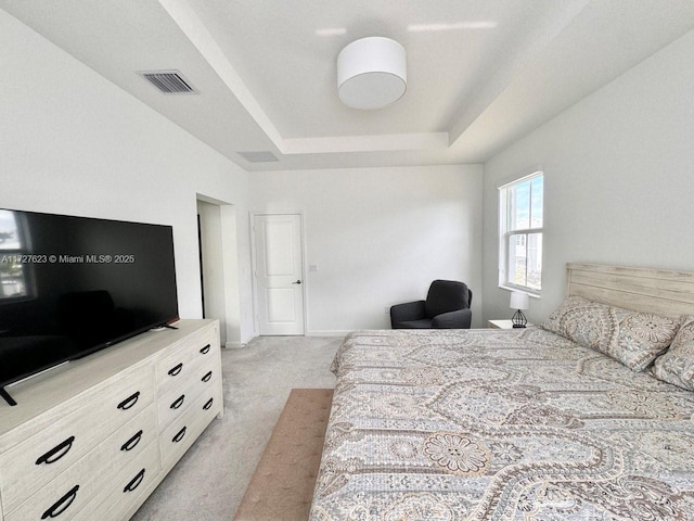 bedroom with a tray ceiling and light carpet