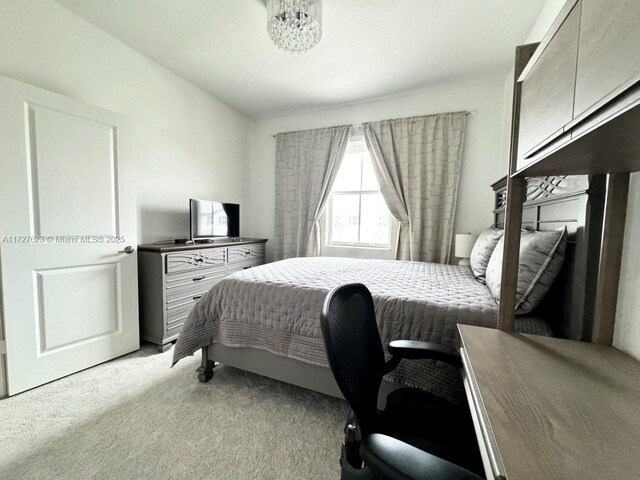 bedroom featuring light colored carpet and a notable chandelier