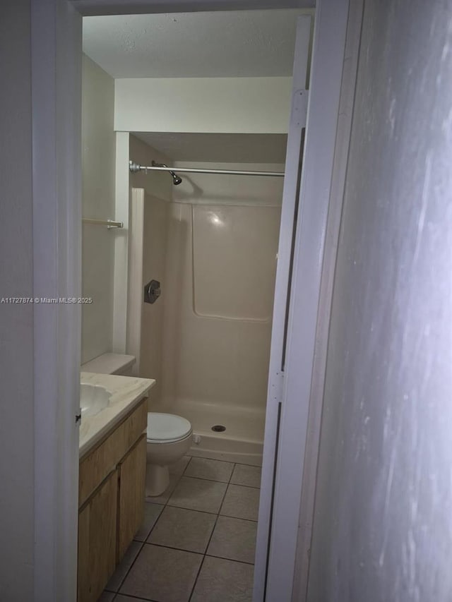 bathroom with toilet, walk in shower, vanity, and tile patterned flooring