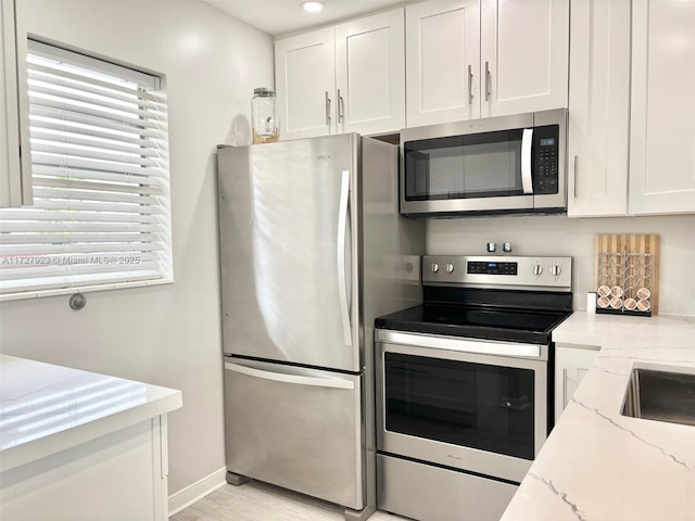 kitchen featuring white cabinetry, light stone counters, plenty of natural light, and stainless steel appliances