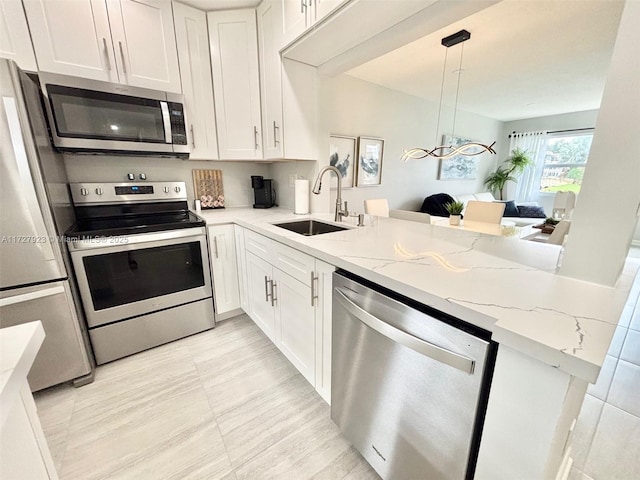 kitchen featuring sink, white cabinetry, decorative light fixtures, appliances with stainless steel finishes, and kitchen peninsula