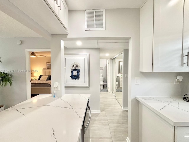 kitchen with light stone counters, ceiling fan, and white cabinets