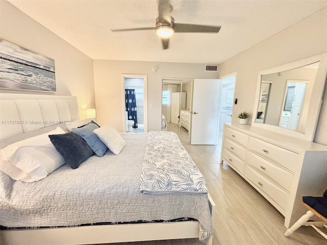 bedroom with ceiling fan, connected bathroom, light hardwood / wood-style flooring, and a textured ceiling