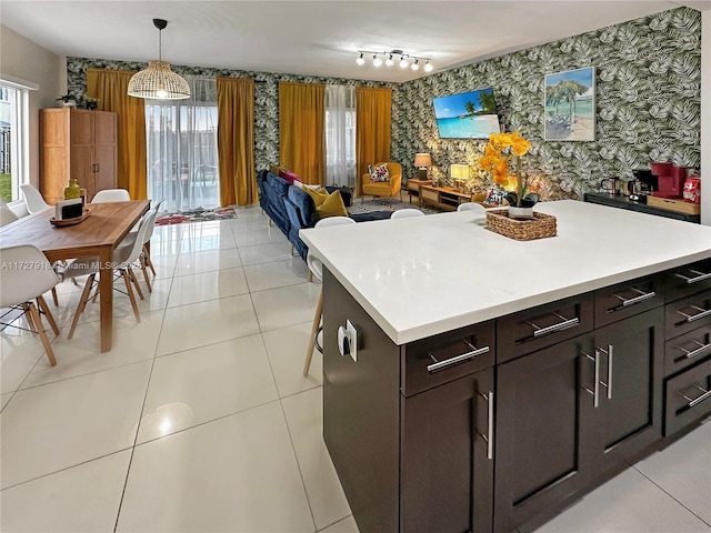 kitchen featuring light tile patterned floors, track lighting, dark brown cabinets, hanging light fixtures, and a kitchen island