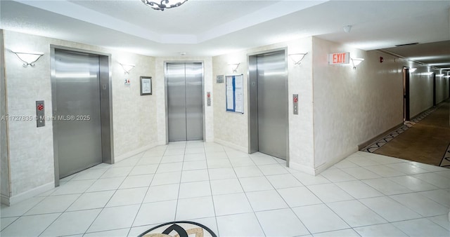 hall featuring light tile patterned flooring and elevator