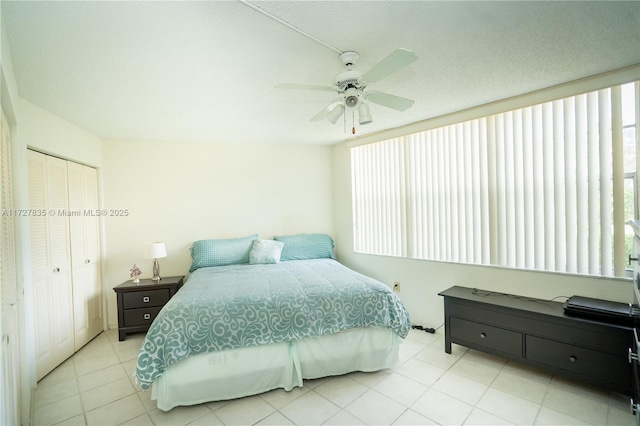 bedroom with ceiling fan, light tile patterned floors, and a closet