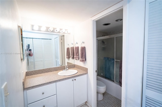 full bathroom featuring toilet, bath / shower combo with glass door, tile patterned floors, and vanity