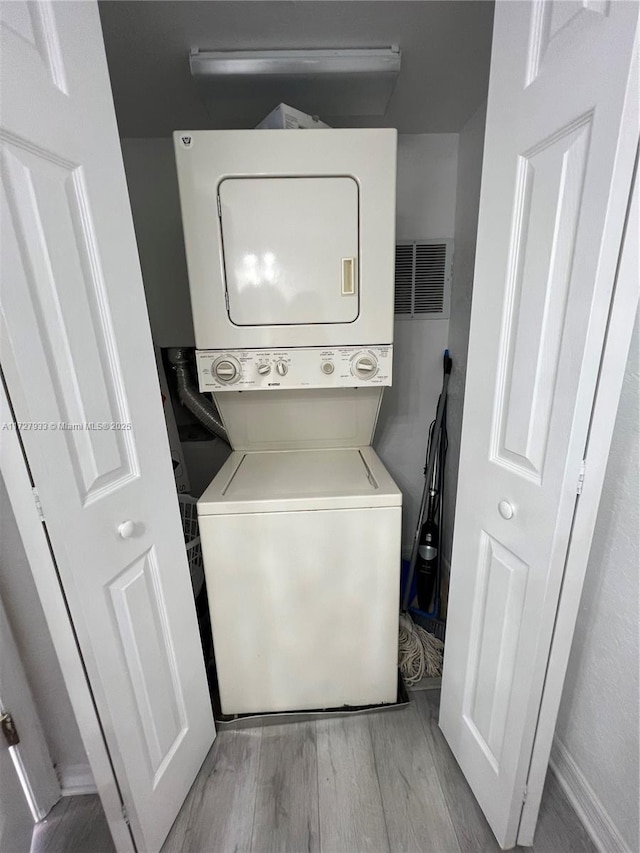 laundry room with stacked washer / drying machine and light hardwood / wood-style floors