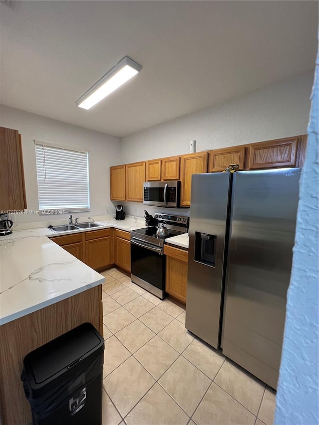 kitchen with light stone counters, sink, light tile patterned floors, and stainless steel appliances