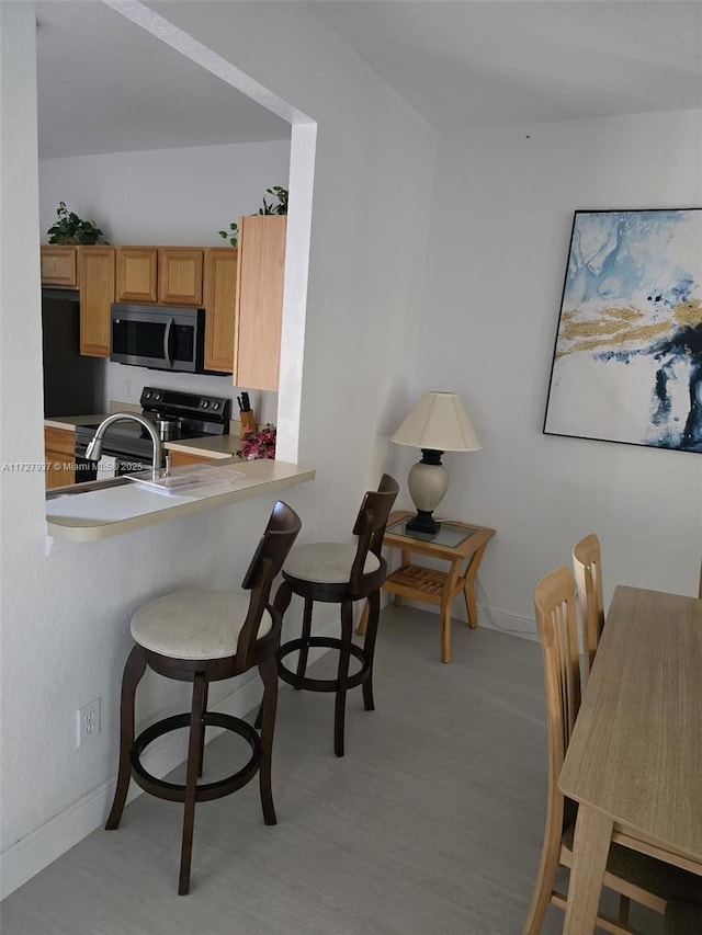 kitchen featuring a kitchen bar, electric stove, and kitchen peninsula