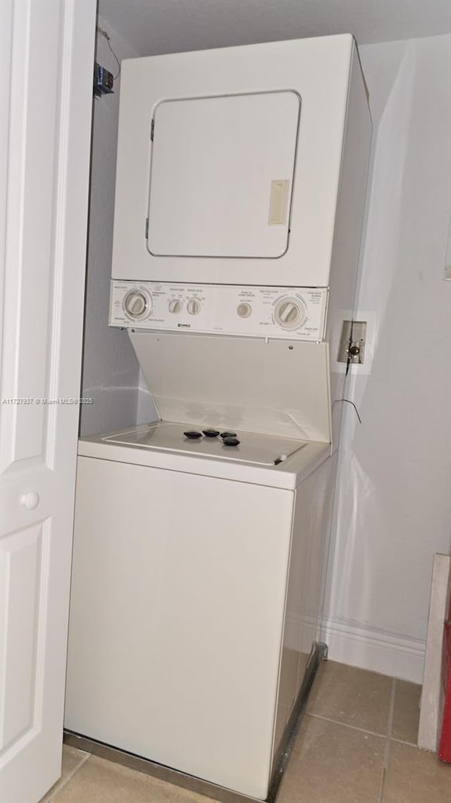 washroom with light tile patterned floors and stacked washing maching and dryer