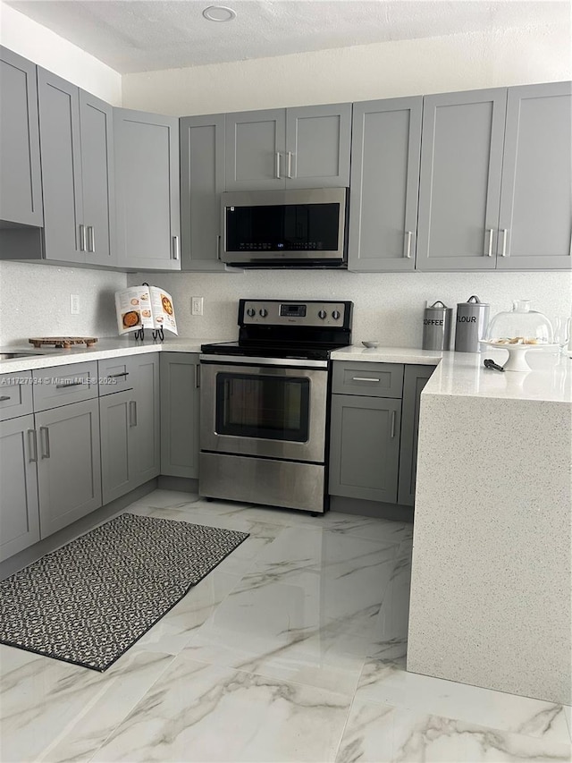 kitchen featuring appliances with stainless steel finishes and gray cabinetry