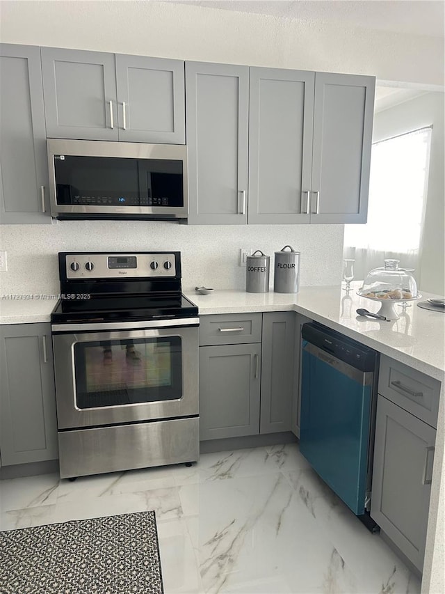 kitchen featuring light stone countertops, appliances with stainless steel finishes, and gray cabinets