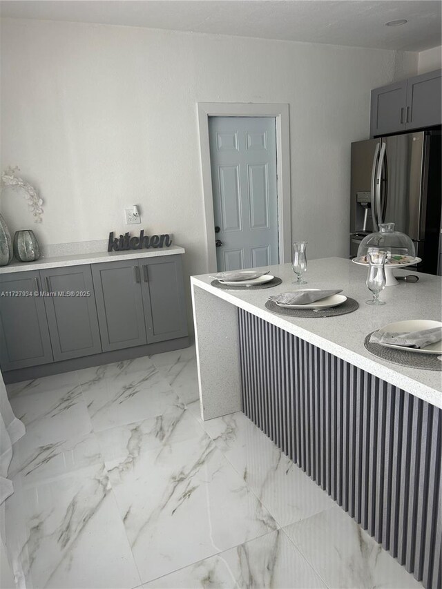 kitchen with gray cabinets and stainless steel fridge with ice dispenser