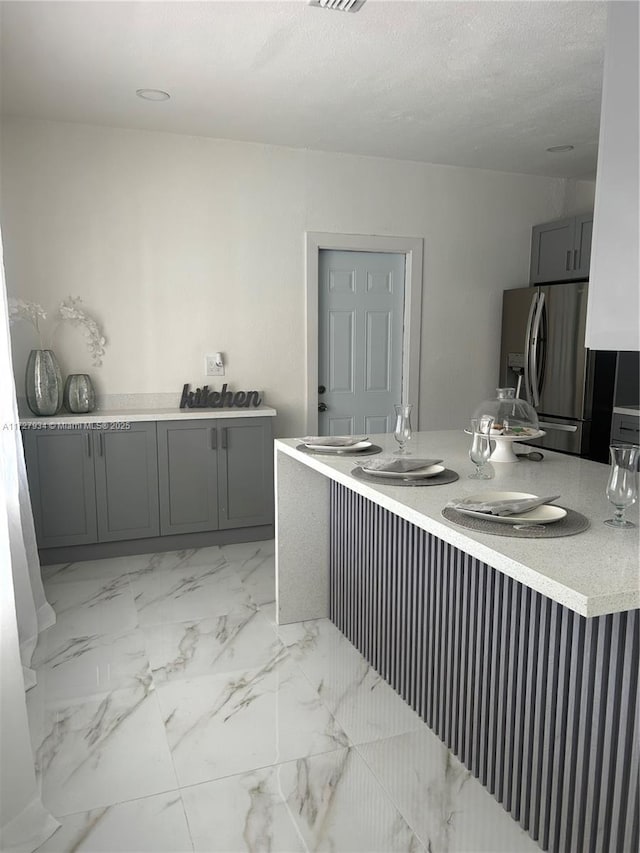 kitchen with gray cabinets and stainless steel fridge with ice dispenser