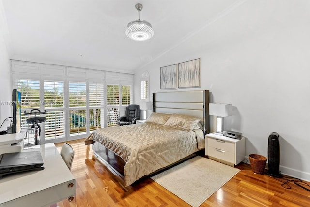 bedroom featuring crown molding, lofted ceiling, and light hardwood / wood-style floors