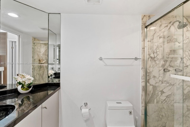 bathroom featuring toilet, vanity, and a shower with door